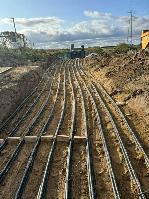 Row of black ducts laid across a sand bed